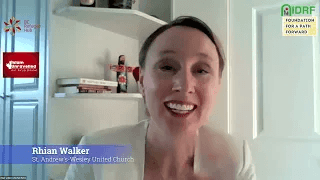 Person smiling in an indoor setting with shelves and books in the background.