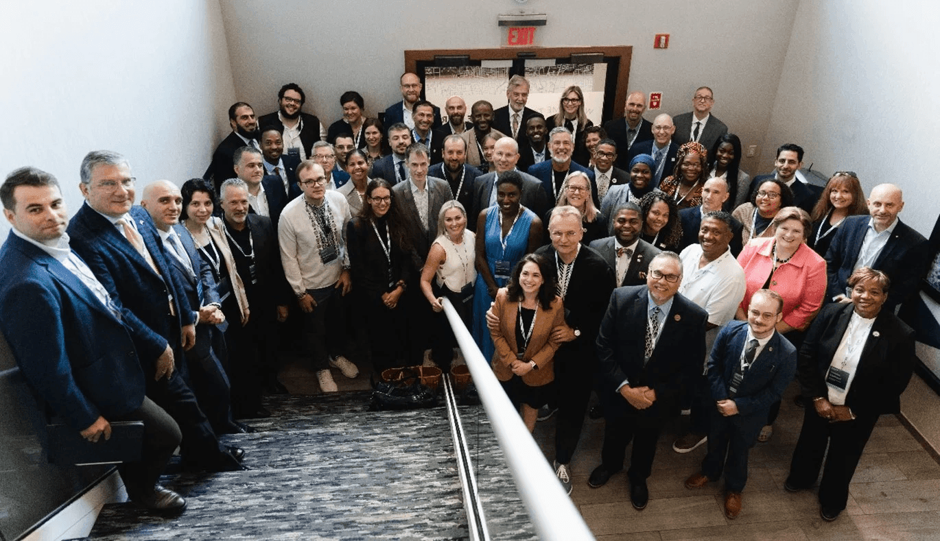 Group of professionals posing on a staircase, wearing business attire and conference badges.