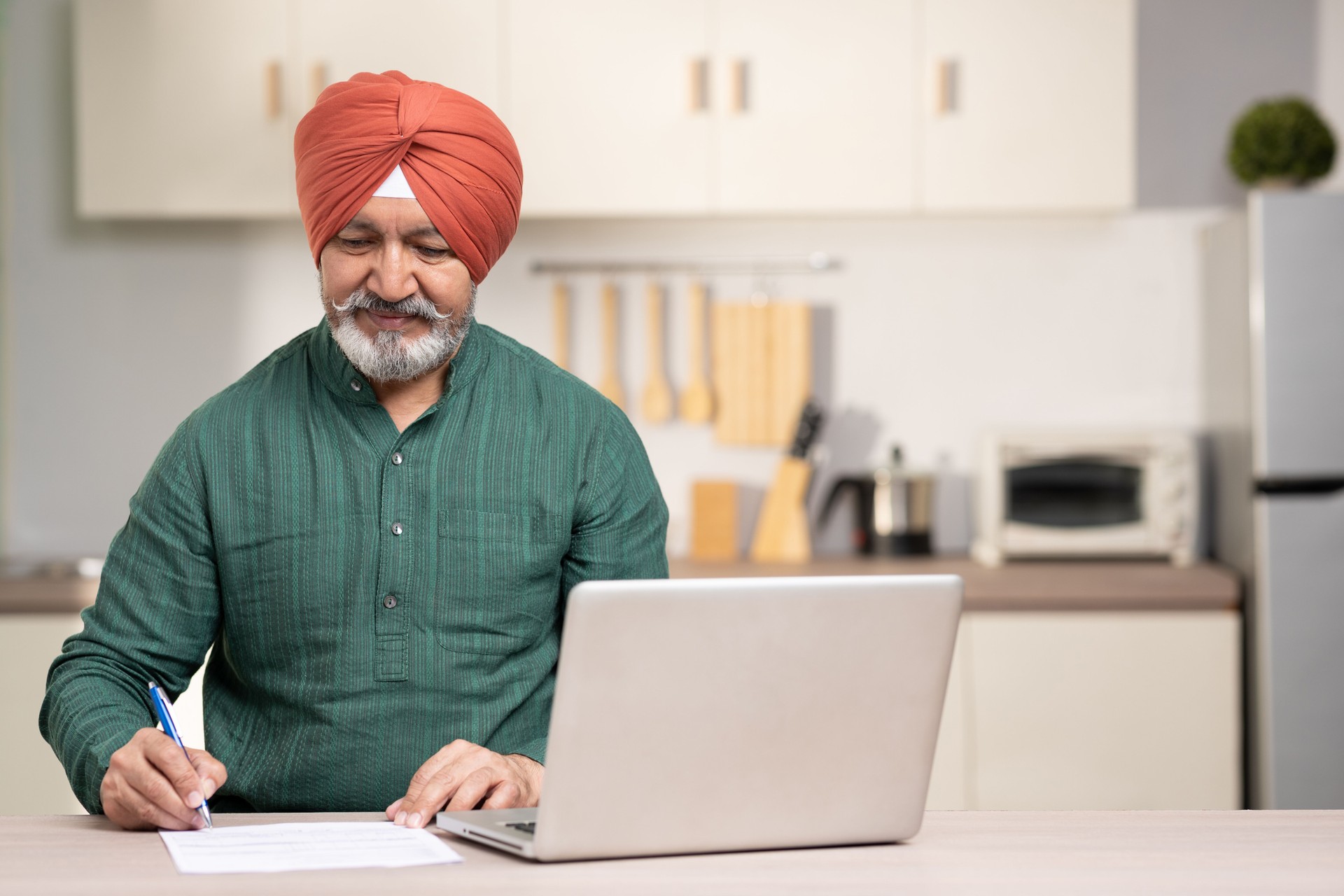 Indian sikh man using laptop at home, stock photo