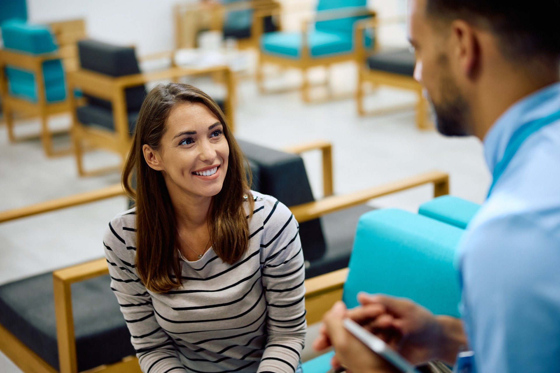 Happy woman talking to medical technician in waiting room at the clinic.